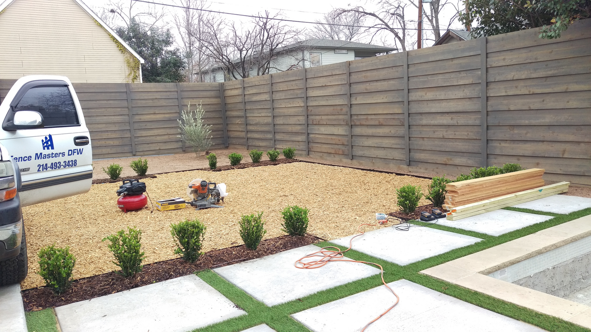 A backyard with grass and concrete pavers.