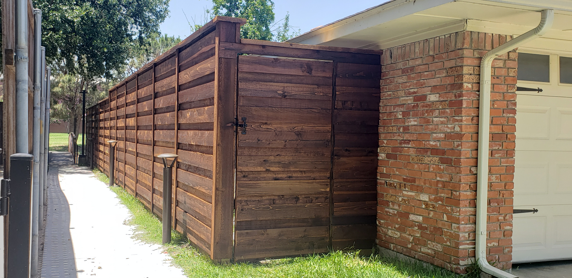 A wooden fence with brick wall and grass.