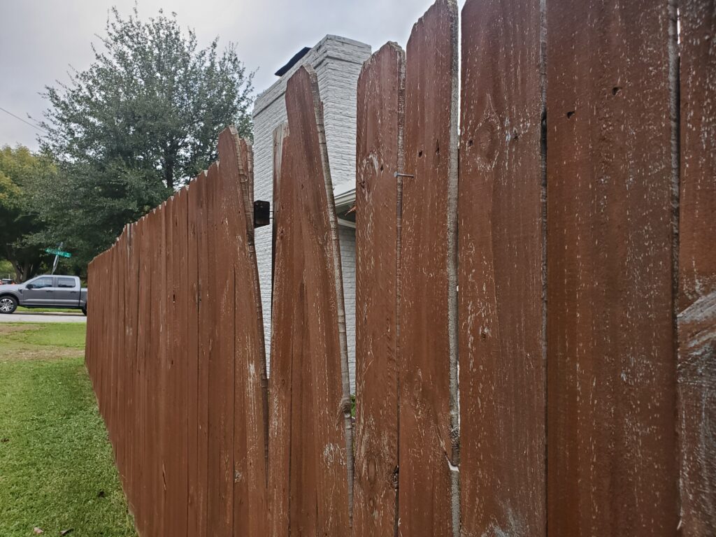 A wooden fence with a house in the background.