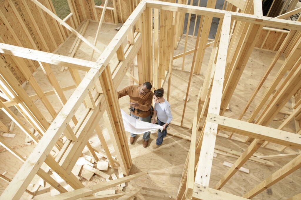 A man and woman in construction site with wood framing.