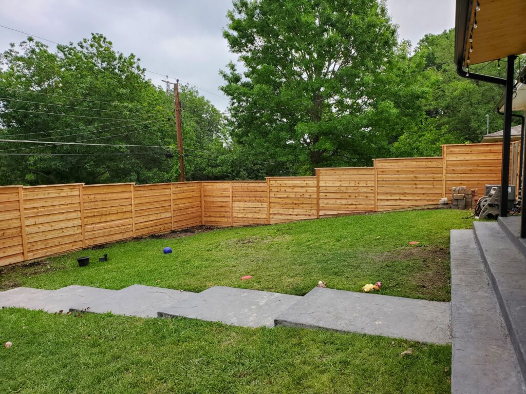 A wooden fence in the middle of a yard.