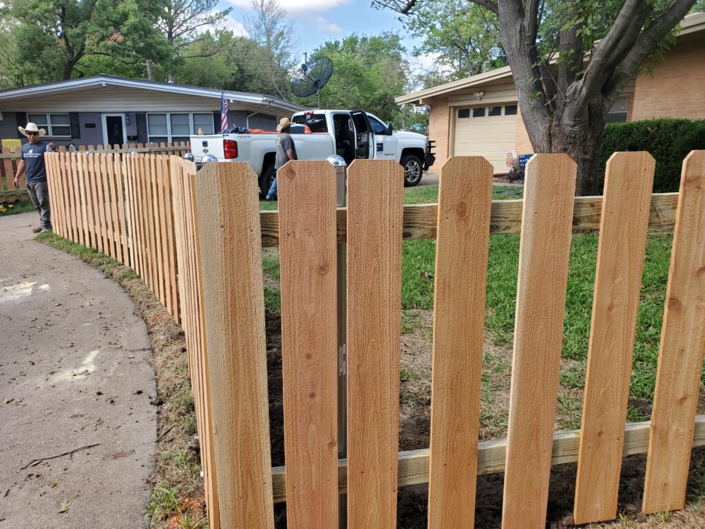 A truck parked in front of a wooden fence.