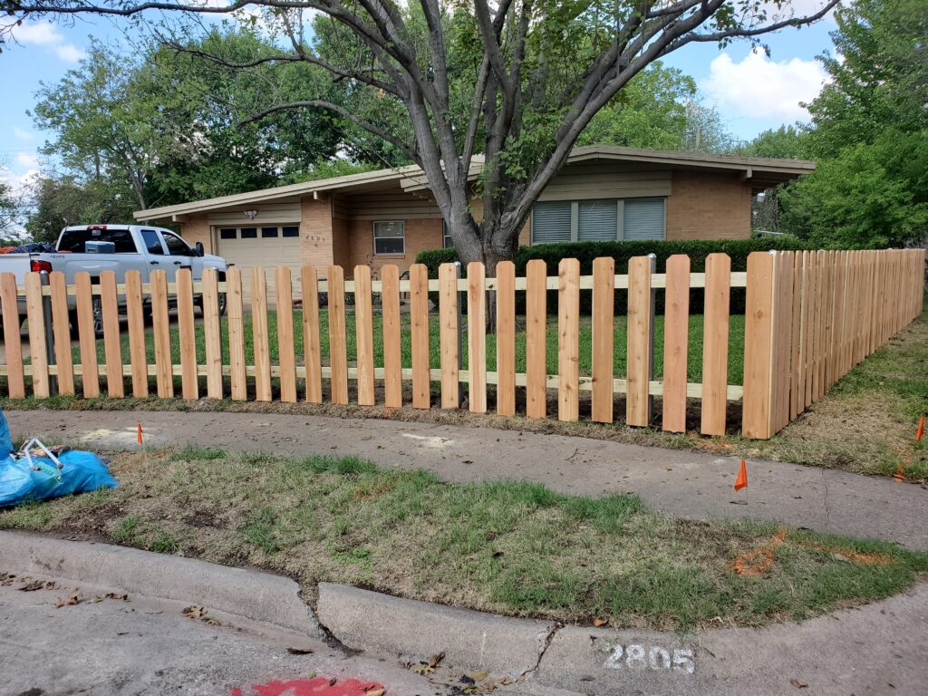 A wooden fence is shown in front of a house.